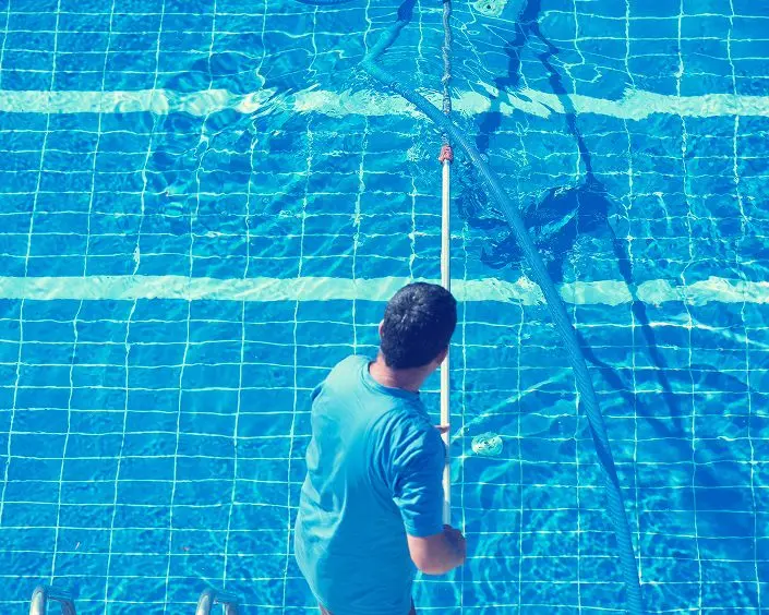 pool technician vacuuming tiled pool floor