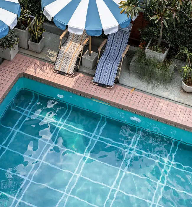 tiled pool striped lounge chairs umbrellas